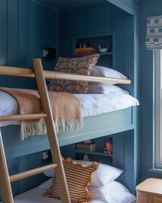 a bunk bed in a room with blue walls and white pillows on the bottom bunk