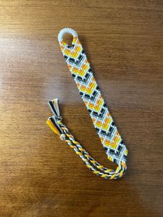 a white and yellow lanyard sitting on top of a wooden table