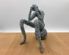 a wire sculpture sitting on top of a wooden table