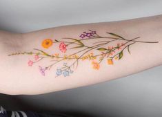 a woman's arm with flowers and butterflies painted on the back of her arm