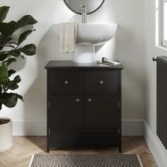 a bathroom with a sink and mirror next to a plant in a pot on the floor