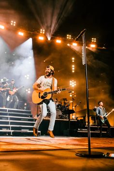 a man standing on top of a stage holding a guitar