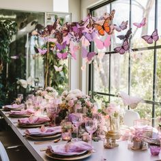 the table is set with pink flowers and butterflies hanging from the ceiling, along with plates and glasses