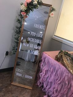 a mirror that is sitting on the floor next to a table with flowers in it