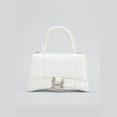 Balenciaga top-handle bag in shiny crocodile-embossed calf leather. Rolled, padded top handle. Removable, adjustable shoulder strap. 3" strap drop; 9" - 23" convertible strap drop Flap top with metal B hardware; snap closure. Exterior, slip compartment at back. Interior, one slip pocket. 5.1"H x 7.5"W x 3.1"D. Made in Italy. Luxury Rectangular Shoulder Bag With Single Handle, Luxury Single Handle Shoulder Bag, Luxury Shoulder Bag Satchel With Single Handle, Luxury Single Handle Shoulder Satchel, Luxury Top Handle Bag With Single Handle, Luxury Handheld Bag With Single Handle, Luxury Handheld Shoulder Bag With Single Handle, Balenciaga Top Handle Bag, White Balenciaga