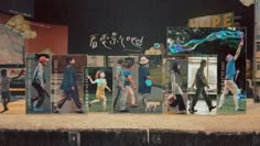 a group of people walking down a street next to tall buildings with advertisements on them