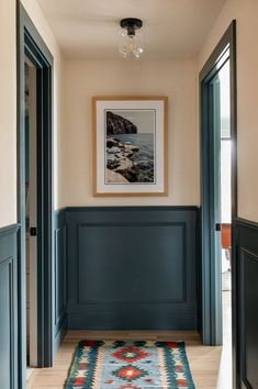 a hallway with blue walls and wood paneling on the floor, along with an area rug