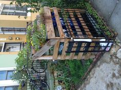 a wooden planter filled with lots of plants next to a fenced in area