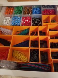 an organized drawer filled with lots of different types of beads and wire in orange trays