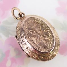 Ornately engraved floral motif designs decorate both sides of this antique 10k solid yellow gold locket pendant. The fully engraved floral reversible pendant features detailed linework, scrolling and floral details, which differs on each side. The locket opens with the help of two tiny knobs and closes securely with a light snap. Inside you will find both original frames attached to glass inserts. The locket tested as 10k gold in three locations (no hallmark). The large added bail at top is gold filled. This antique lovingly aged piece is in very good condition for its turn-of-the-century age. It has some expected surface wear and a few tiny dings to its outer shell. There are two dark lines where the trim was joined on each panel. Please see photos for condition and detailed measurements Antique Medallion Locket Necklace Stamped 14k, Ornate Engraved Medallion Locket Necklace, Victorian Yellow Gold Locket Necklace With Filigree, Victorian Filigree Locket Necklace In Yellow Gold, Victorian Engraved Rose Gold Locket Necklace, Victorian Filigree Yellow Gold Locket Necklace, Ornate Engraved Round Pendant Locket Necklace, Ornate Engraved Round Locket Necklace, Vintage Etched Rose Gold Jewelry