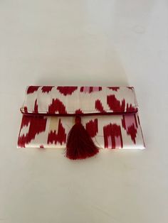 This silk ikat clutch bag will make a great birthday gift for the ladies in your family. It combines the modern and traditional, the practical and artistic. Use it as an accessory that will turn heads and make every outfit stand out. The bag is decorated with a fashionable tassel. Put your keys, phone and some special secret things in it and you'll complete that chic look you need for that big occasion or long-awaited party.  The traditional ikat fabric is handwoven with a lot of care in small v Red Rectangular Clutch For Festivals, Multicolor Woven Clutch As A Gift, Multicolor Woven Clutch As Gift, Woven Pouch Clutch As Gift, Handwoven Rectangular Clutch For Gift, Artisan Rectangular Clutch As A Gift, Handwoven Pouch Clutch For Gift, Handwoven Pouch Clutch As Gift, Handmade Red Clutch As Gift