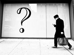 a man walking down the street while looking at his cell phone with a question mark on it