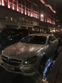 a silver car parked on the side of a street next to tall buildings at night