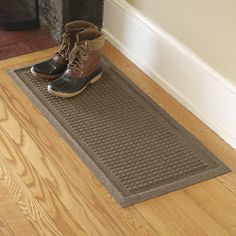 a pair of brown boots sitting on top of a mat next to a fire place