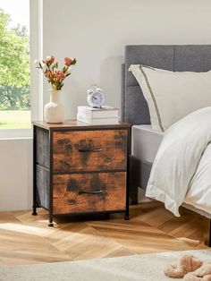 a bedroom with a bed, nightstand and flowers on the table in front of it