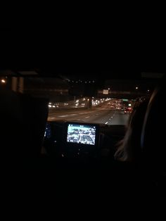 a person is driving in the dark at night with a television on their headrest