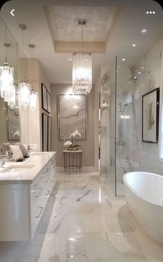 an elegant bathroom with marble floors and white fixtures, chandelier, bathtub