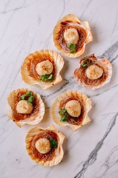 several scallop shells with banana slices and sauce on the top, sitting on a marble surface