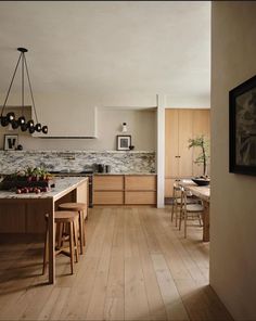 a large kitchen with wooden floors and white walls, along with an island in the middle