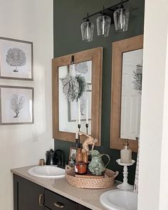 a bathroom with two sinks, mirrors and pictures on the wall above them is shown