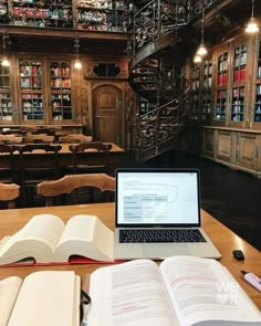 an open laptop computer sitting on top of a wooden table in front of a bookshelf