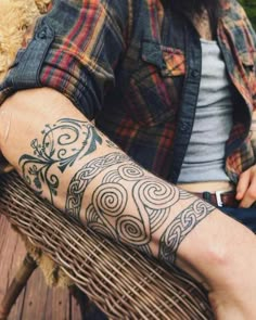 a man with a tattoo on his arm sitting next to a teddy bear