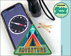 an iphone with the words adventure on it next to a camera and some pencils