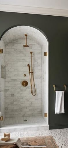 a bathroom with an arched shower door and white tile flooring, along with a rug on the floor