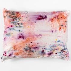 a pink and purple pillow on a white background with lots of paint splatters