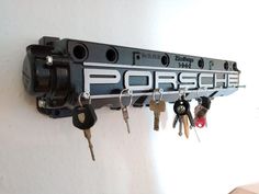 a bunch of keys are hanging on a wall with the word porsche written on it