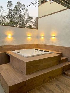 an outdoor jacuzzi tub with lights on the wall and wooden steps leading up to it