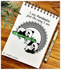 a spiral notebook with pandas on it next to a pen and some green leaves