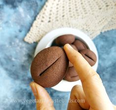 a person holding a chocolate cookie in their hand