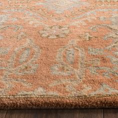 an orange and blue area rug on the floor with wood floors in front of it