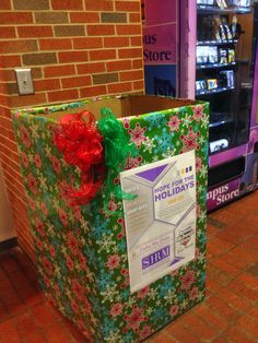 a holiday present wrapped in green and red paper with a bow on it sitting next to a vending machine