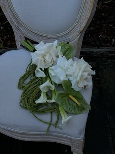 white flowers sit on the back of an old chair with green leaves and stems attached to it