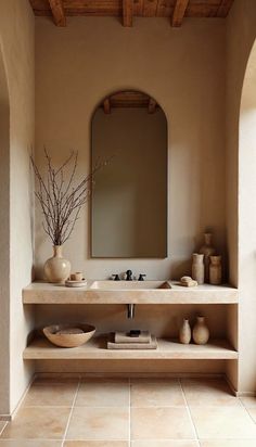 a bathroom with a sink, mirror and vases on the counter in front of it