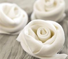 three small white roses sitting on top of a wooden table