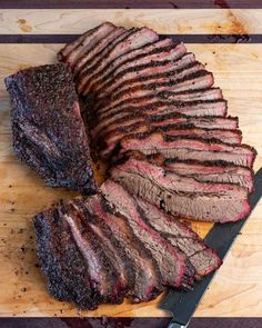 sliced up steak on cutting board with knife and fork next to cut in half meat