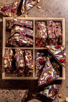 a wooden box filled with assorted candy bars on top of a cement floor next to nuts