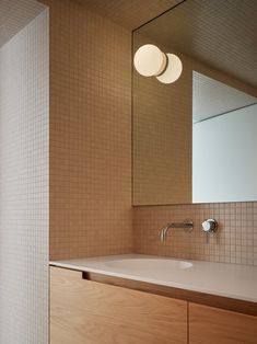 a bathroom sink sitting under a mirror next to a wall mounted faucet with two lights on it