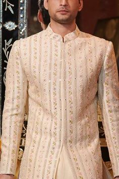 Cream sherwani with thread, pearl, cutdana and mirror work. Comes with raw silk straight pants.
Component: 2
Pattern: Embroidery
Type Of Work: Thread, Pearl, Mirror and Cutdana
Neckline: Band
Sleeve Type: Full
Fabric: Chanderi and Raw Silk
Color: Cream
Other Details: 
Slit in front and the sides
Note: Inner kurta worn by the model is not for sale
Occasion: Wedding - Aza Fashions Sawan Gandhi, Cream Sherwani, Raw Silk Embroidery, Pearl Mirror, Pattern Embroidery, Silk Embroidery, Mirror Work, Pant Set, Straight Pants