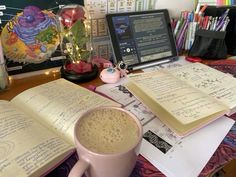 an open book sitting on top of a desk next to a cup of coffee