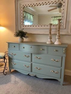 a blue dresser sitting in front of a mirror on top of a floor next to a lamp