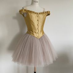 a mannequin dressed in a gold and white tulle skirt with buttons on the shoulders