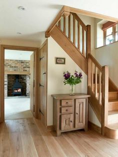 a vase with flowers sitting on top of a wooden table next to a stair case