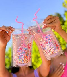 two girls holding up plastic cups with sprinkles on them