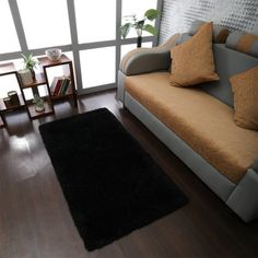 a living room filled with furniture and a black rug on top of a hard wood floor