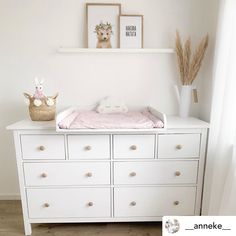 a baby's crib in the corner of a room with pictures on the wall