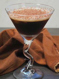 a glass filled with liquid sitting on top of a table next to a brown cloth